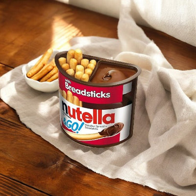 A 1.8 oz container of Nutella and Go Breadsticks - 1 count by Nutella is placed on a wooden surface next to a white cloth. A small bowl of additional breadsticks is in the background, perfectly complementing the hazelnut spread for an ideal snack.