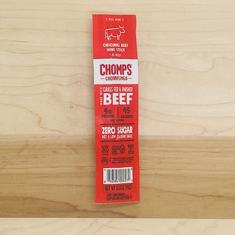 On a wooden surface lies a packaged beef stick labeled "Chomps," specifically the Chomp Chomplings Original Beef - 0.5 oz - 1 Count. It boasts details such as grass-fed, zero sugar, 45 calories, and 4g of protein, epitomizing healthy meat snacks made from sustainably sourced proteins.