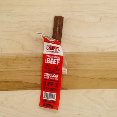 A Chomp Chomplings Original Beef stick, weighing 0.5 oz and featuring a partially unwrapped red and white label on a wooden surface, offers a tasty gluten-free option for those seeking healthy meat snacks.