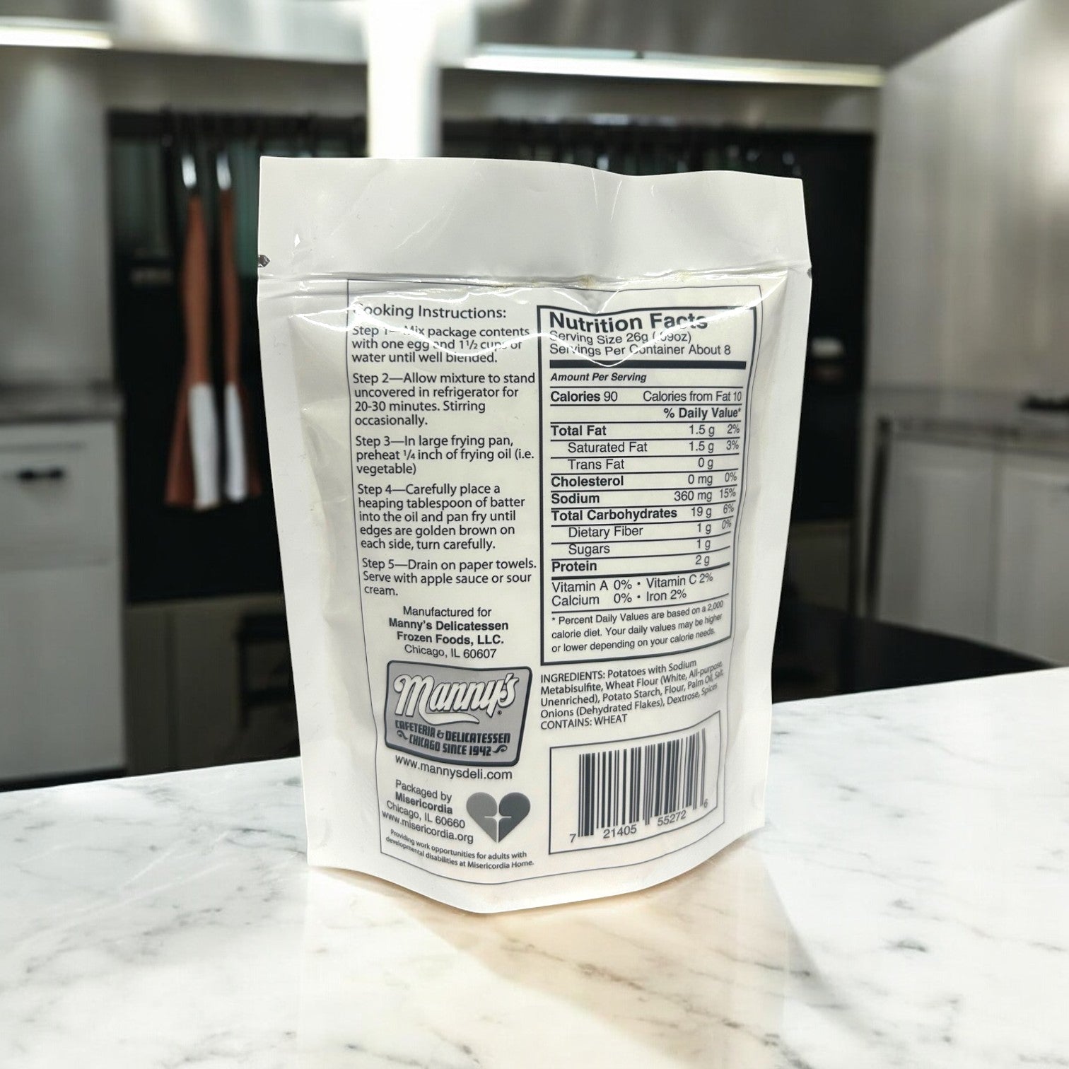 The back of Manny's Potato Pancake Mix-3 Count package shows cooking instructions and nutrition facts for homemade potato pancakes, next to the Manny's brand logo, on a kitchen counter.