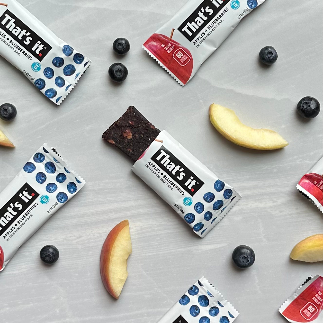 That's it. Gluten-Free Soft & Chewy Blueberry Mini's Ready-to-Eat Fruit Bars, surrounded by fresh apple slices and whole blueberries, arranged on a light-colored surface, make for the perfect all-natural snack from an allergen-free facility.