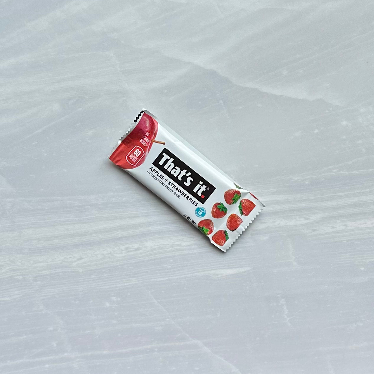 A packaged "That's it" Strawberry Mini Fruit Bars with strawberry graphics on a light gray surface. The label indicates it is an apple and strawberry flavor, making it a perfect gluten-free and plant-based snack.