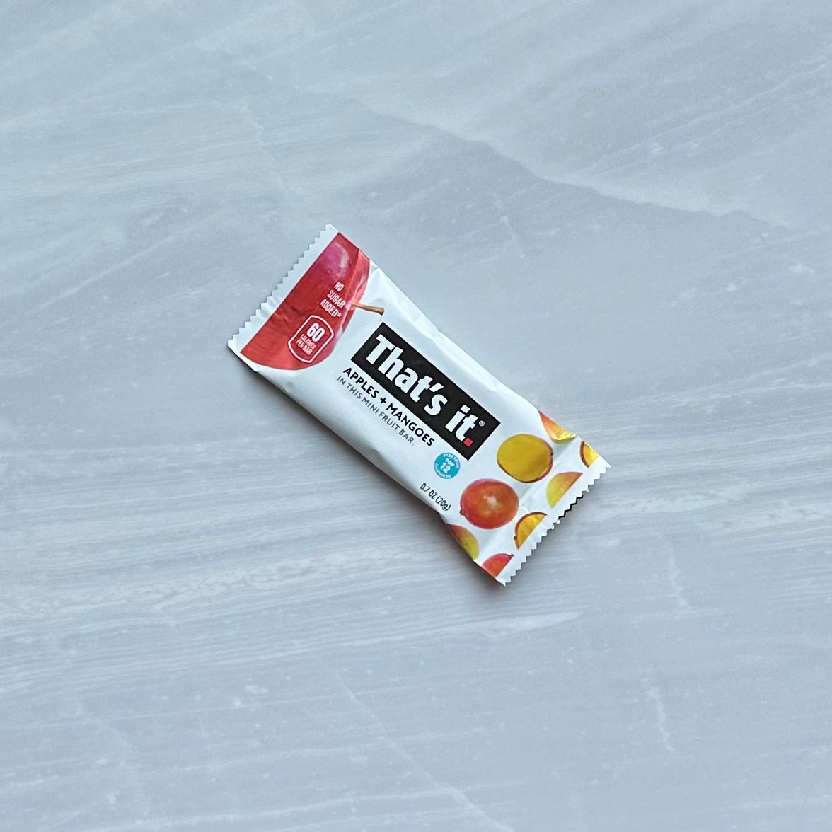 A small, packaged fruit bar from the brand "That's it" called "That's it. Gluten-Free Soft & Chewy Mango Mini Fruit Bars." This vegan bar is apple-mango flavored, made from 100% natural fruit, gluten-free and dairy-free, with images of apples and mangoes on the wrapper.