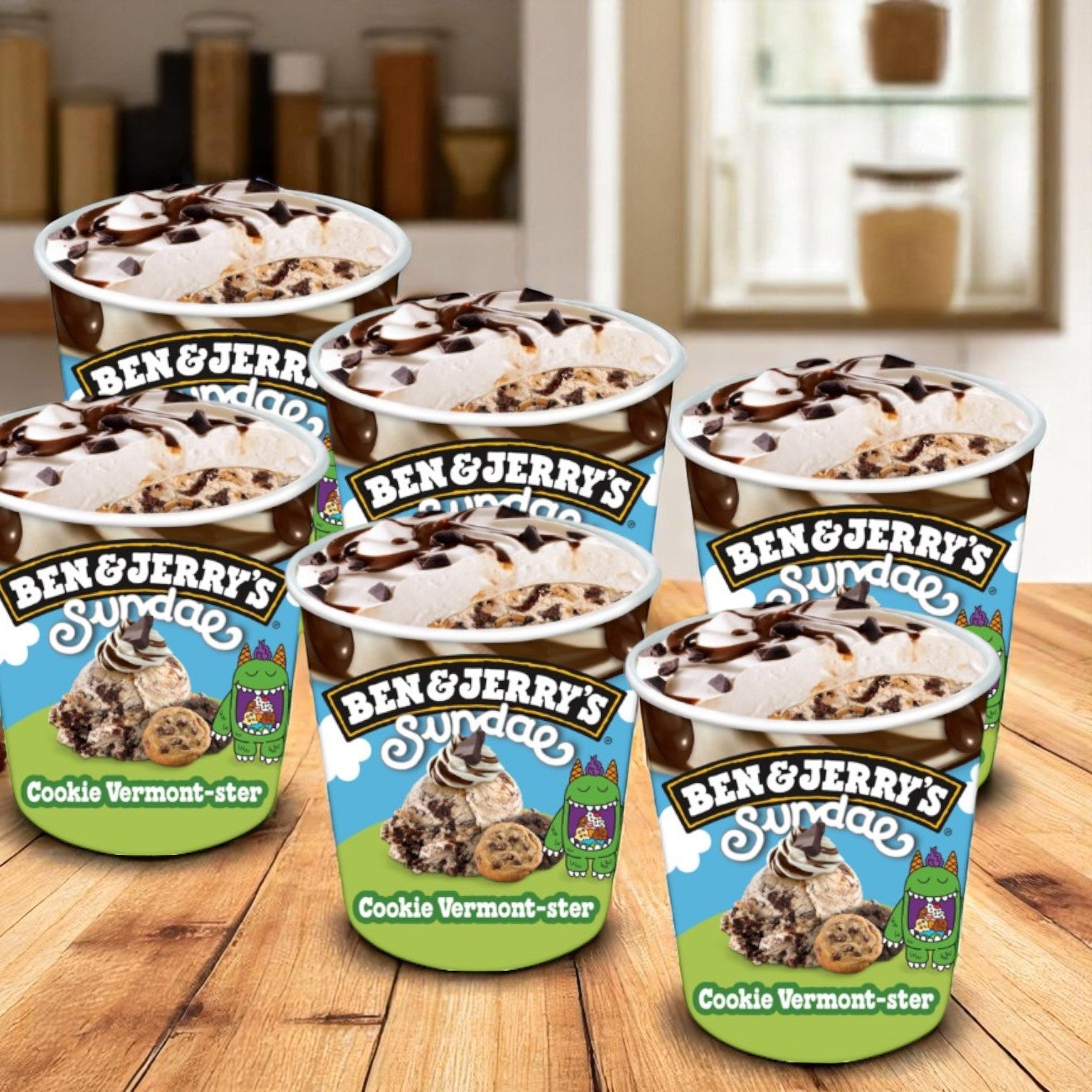 Six pints of Ben & Jerry's Ice Cream, Cookie Vermont-Ster Sundae (14.4 fl oz each) are displayed on a wooden surface in a cozy kitchen setting.