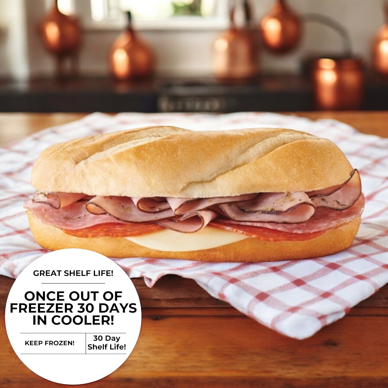 An Italian Style Sub from E.A. Sween is displayed on a checkered cloth, with a sticker advising, "Once out of freezer 30 days in cooler. Keep frozen! 30 day shelf life," while copper pots gleam in the background.