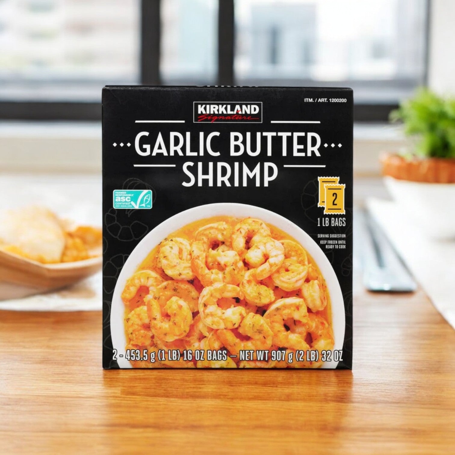 A package of Costco Kirkland Signature Garlic Butter Shrimp, 2-count with 3 bags, is placed on a kitchen table, ideal for seafood enthusiasts looking for convenient preparation.