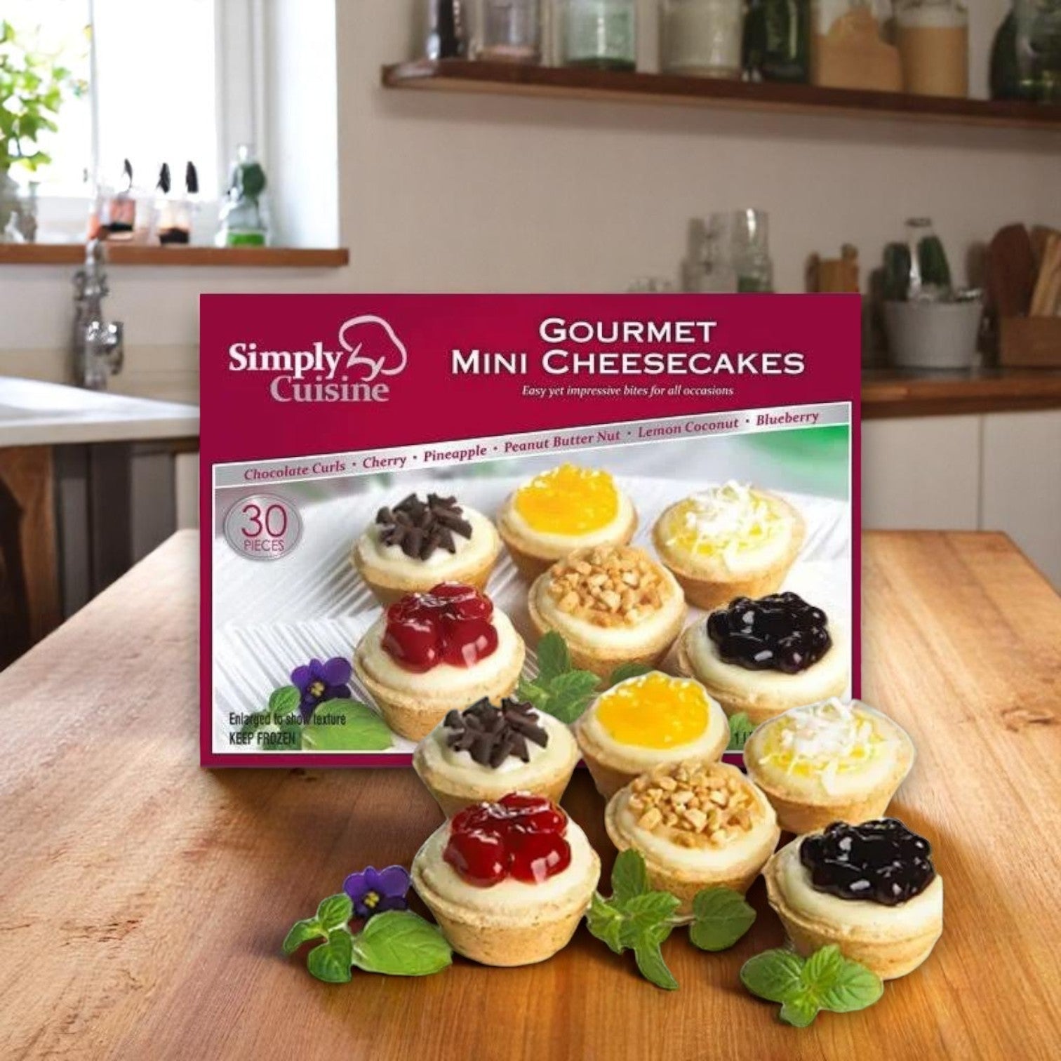 A box of Cuisine Innovations Mini Assorted Cheesecakes, 30 Count, rests on a kitchen table with the bite-sized treats attractively arranged in front of the box.