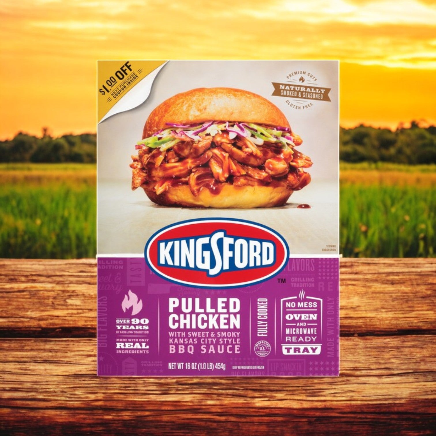 A 16 oz box of Kingsford Pulled Chicken with rich BBQ flavor is displayed enticingly on a wooden table, featuring a tempting sandwich image against a lush grassy backdrop.