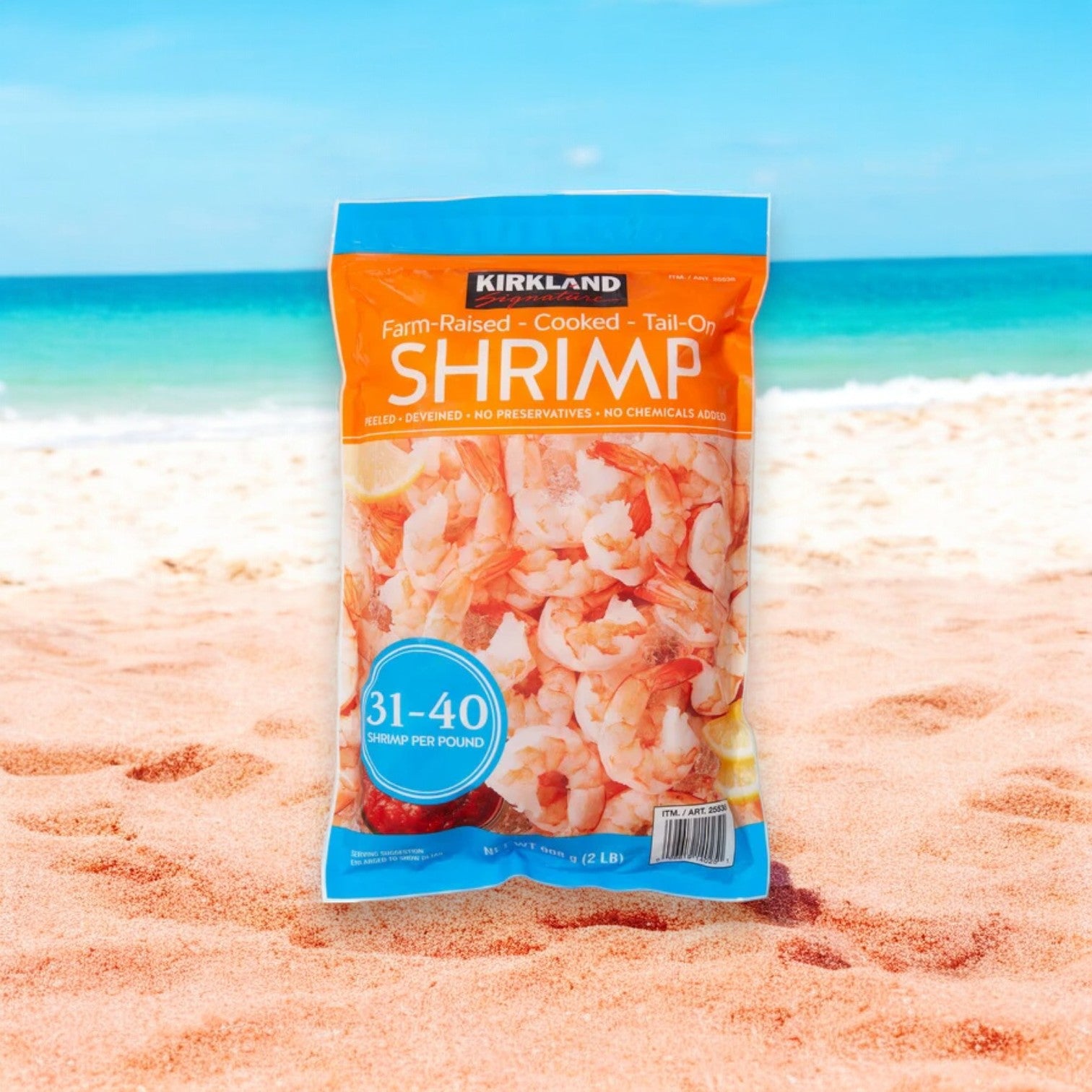 A package of Kirkland Signature Farm-Raised Cooked Shrimp, tail-on, peeled, and deveined with a 31-40 count per bag, stands proudly on a sandy beach, while the ocean waves gently whisper in the background.