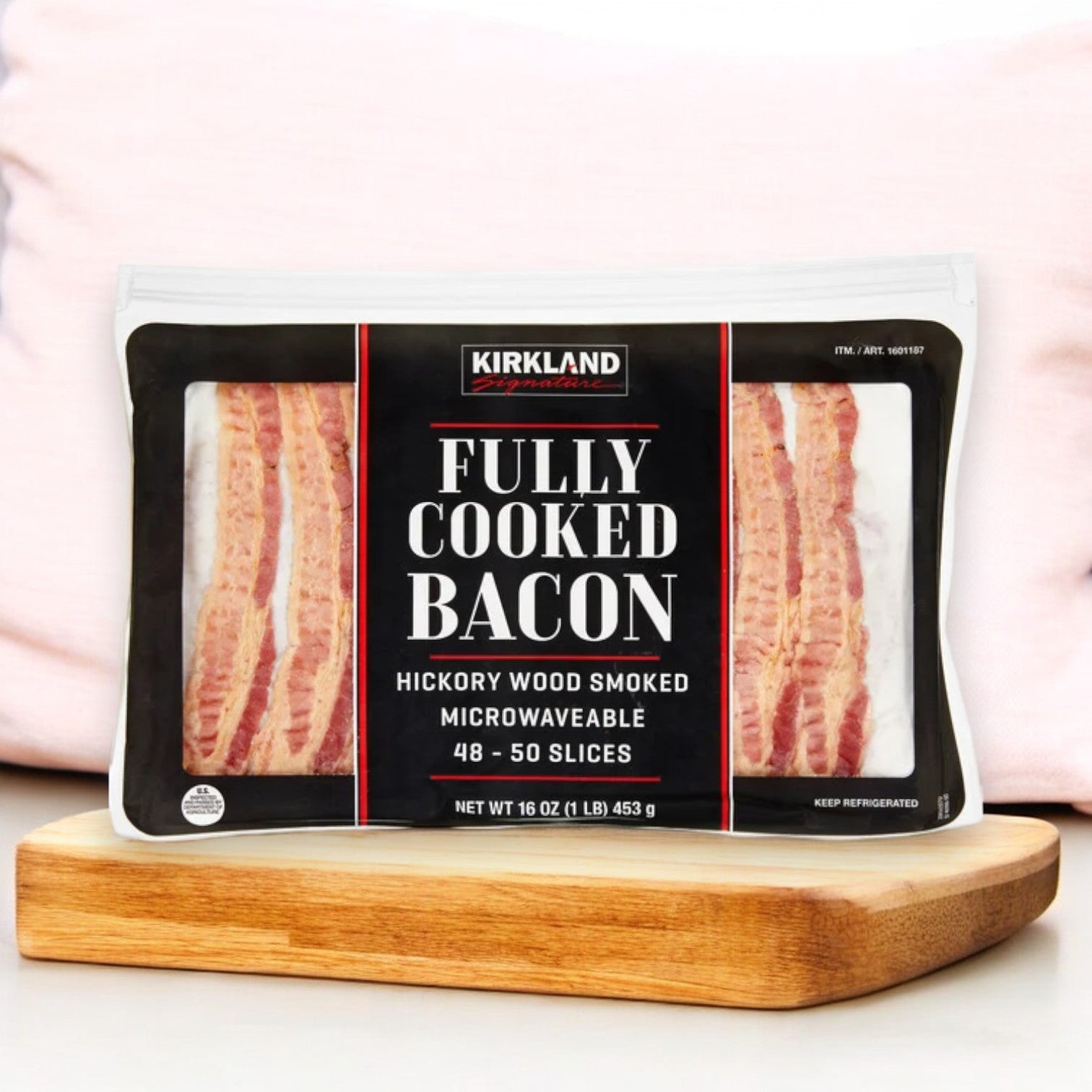 The Kirkland Signature Fully-Cooked Bacon, expertly hickory wood smoked and crafted with premium ingredients, is available in a convenient microwavable package containing 1 lb per pack and comes in a set of three packs weighing a total of 3 pounds, all attractively showcased on a wooden surface.