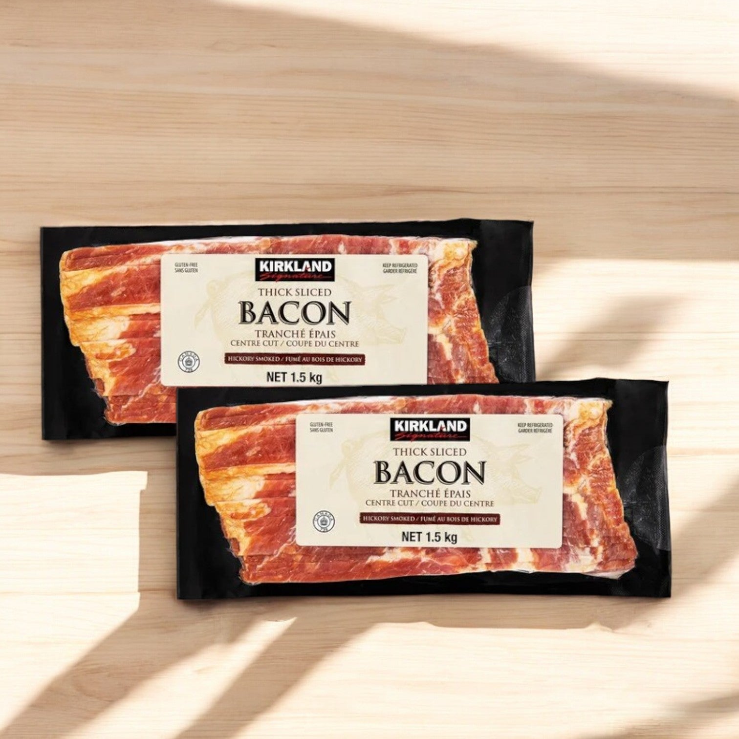 Three packs of Easy Lunches Kirkland Signature Thick Sliced Bacon (two 1.5 lb packs each, 9 lbs total) are displayed side by side on a light wooden surface, highlighting their thick-sliced bacon appeal.