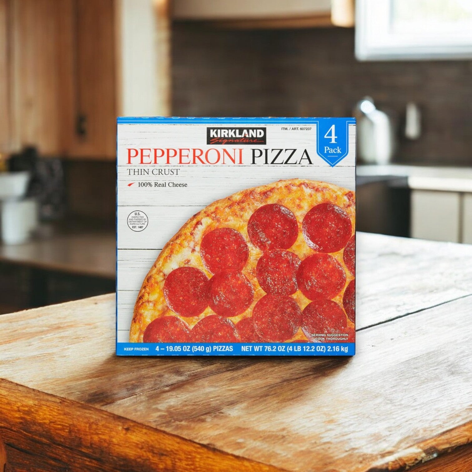 A pack of Kirkland Signature Pepperoni Pizza, measuring 19.05 oz and including four pizzas, sits on a wooden kitchen counter, adorned with premium pepperoni and creamy mozzarella cheese.