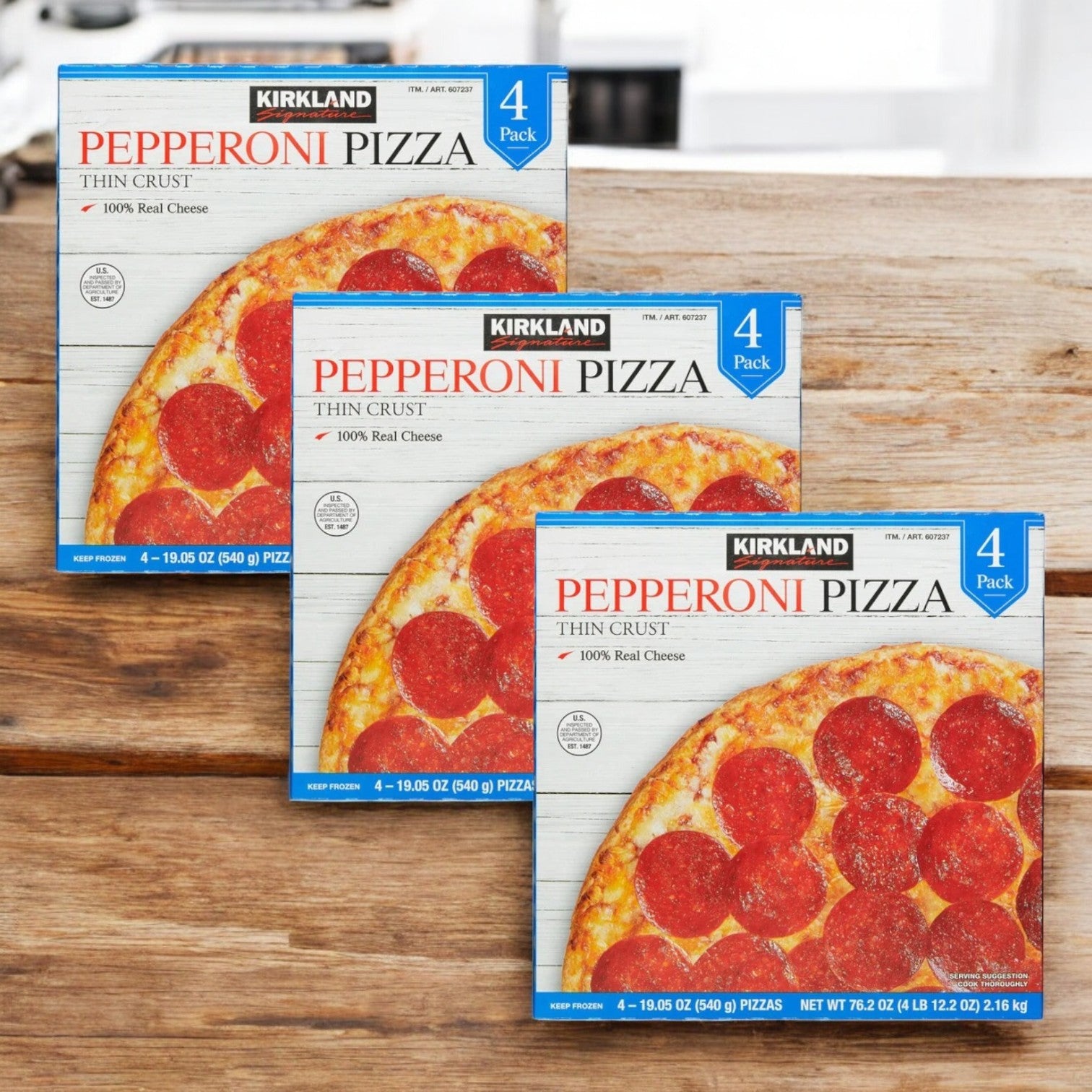 Three 3-packs of Kirkland Signature Pepperoni Pizza, each containing four crispy-crust pizzas with premium pepperoni and "100% Real Cheese," are displayed on a wooden surface.
