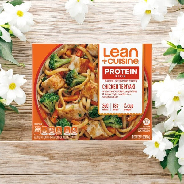 A Lean Cuisine Noodle Bar Chicken Teriyaki Bowl, 8.5 oz. - 1 Count package sits on a wooden surface surrounded by white flowers.