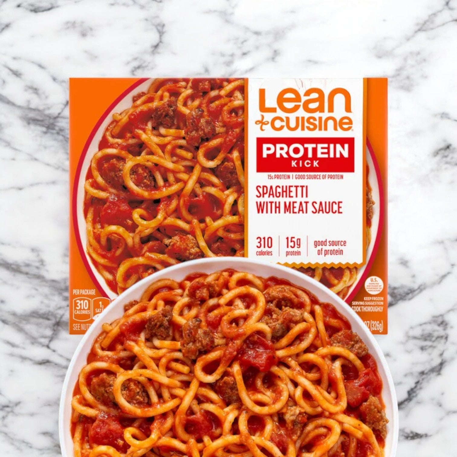 A Lean Cuisine Spaghetti with Meat Sauce with Mushrooms and Basil package placed above a plate of the same low-calorie spaghetti and meat sauce on a marble surface.