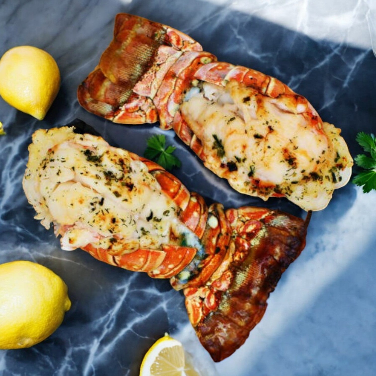 Two succulent Sysco Lobster Tail North Atlantic Premium 6-7 Ounce delicacies rest on a marble surface garnished with fresh herbs, surrounded by premium lemons and vibrant parsley, creating an enticing and mouth-watering display.