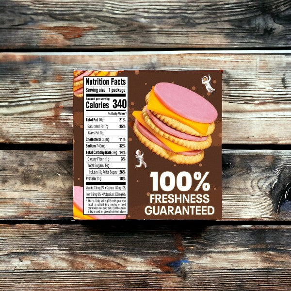 A Lunchables Ham & Cheddar Cheese, 3.5 oz. - 1 Pack sitting on a wooden surface shows nutritional facts alongside an enticing image of crackers topped with pink ham and cheddar cheese slices. The text boldly proclaims "100% Freshness Guaranteed" in white letters. Ideal for on-the-go meals, this convenient snack from Lunchables ensures you enjoy freshness every time.