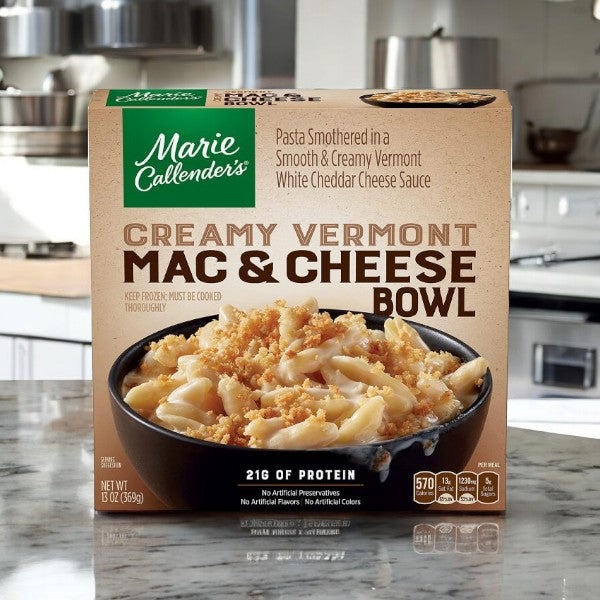 Image of a Marie Callender's Mac and Cheese package from the Marie Calendar Meals Bundle, placed on a kitchen counter. The packaging describes it as pasta with aged cheddar cheese sauce, containing 21g of protein.