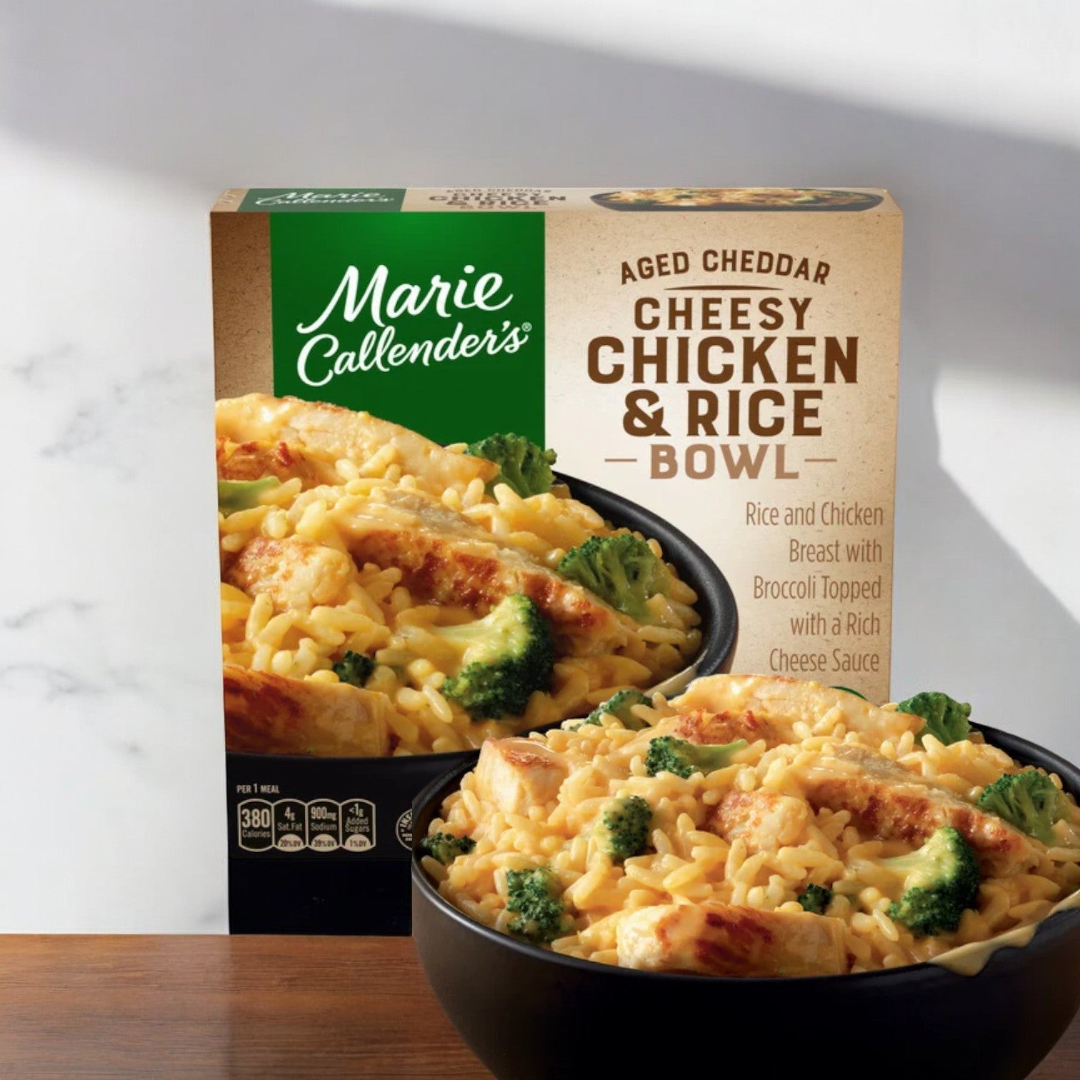 Close-up of Marie Callender's Aged Cheddar Cheesy Chicken and Rice Bowl, 12 oz. - 1 Count packaging. It displays rice, chicken breast, broccoli, and cheese sauce in a bowl with nutritional information and the product name clearly visible. A perfect comforting meal from Marie Callender's.