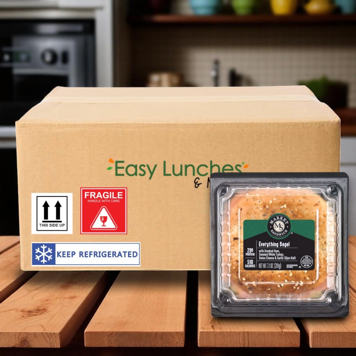 A cardboard box labeled "Market Sandwich Everything Bagel, Ham, Turkey, Swiss Cheese & Garlic Dijon Aioli" from E.A. Sween sits on a kitchen counter next to an individually wrapped 7.1 oz sandwich with visible nutrition and storage labels.
