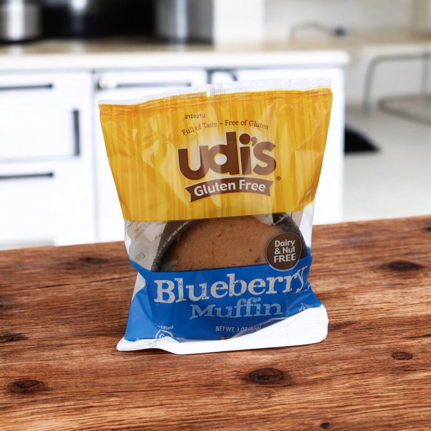 An individually wrapped 3 oz. Udi's blueberry gluten-free muffin from a case of 36 is enticingly placed on a wooden kitchen table, ready to be enjoyed.