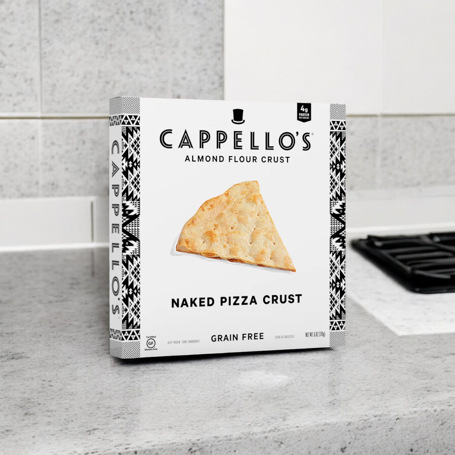 A box of Cappello's Grain Free Naked Pizza Crust, 6 oz. - 1 Case, 6 Packs, is positioned on the kitchen counter near the stove, ready to create a delicious gluten-free pizza masterpiece.