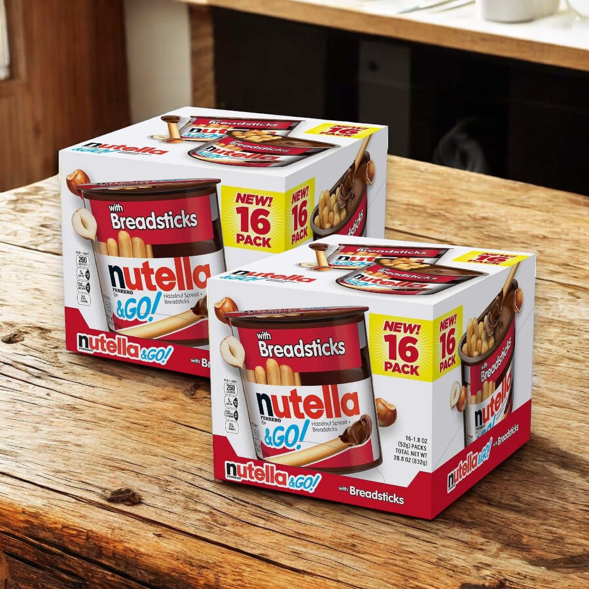 Two boxes of Easy Lunches Nutella and Go Hazelnut Spread with Breadsticks Ferrero, each containing 16 packs, are displayed on a wooden counter. The packaging prominently highlights "NEW! 16 PACK" and features the Nutella and Go product with breadsticks. Each pack is 1.8 oz, making for a total of 32 packs.