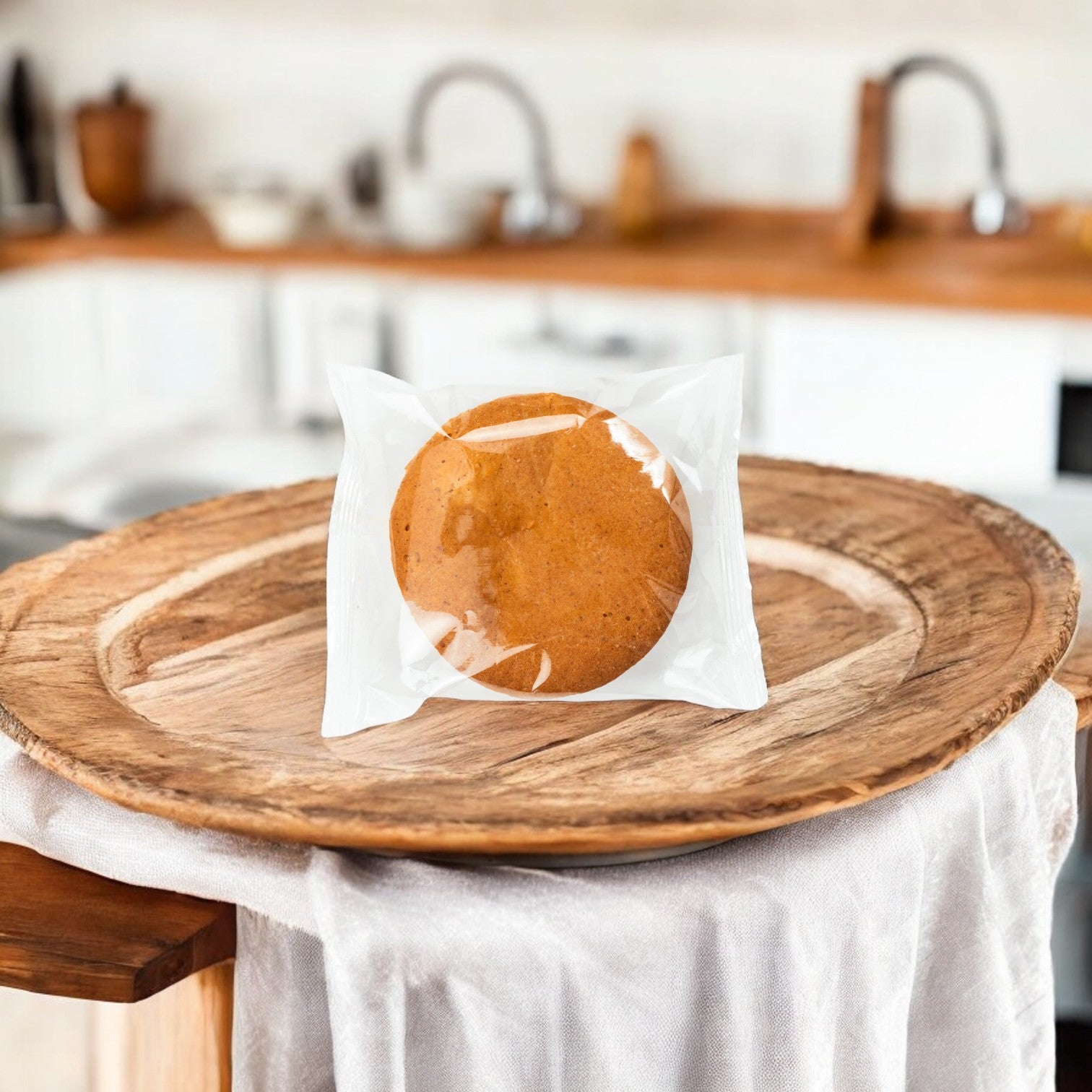 A delightful experience is guaranteed with the "OMG It's Gluten Free, Hamburger Bun," carefully positioned on a wooden tray covered with a cloth, in a warm kitchen ambiance with a softly blurred background.