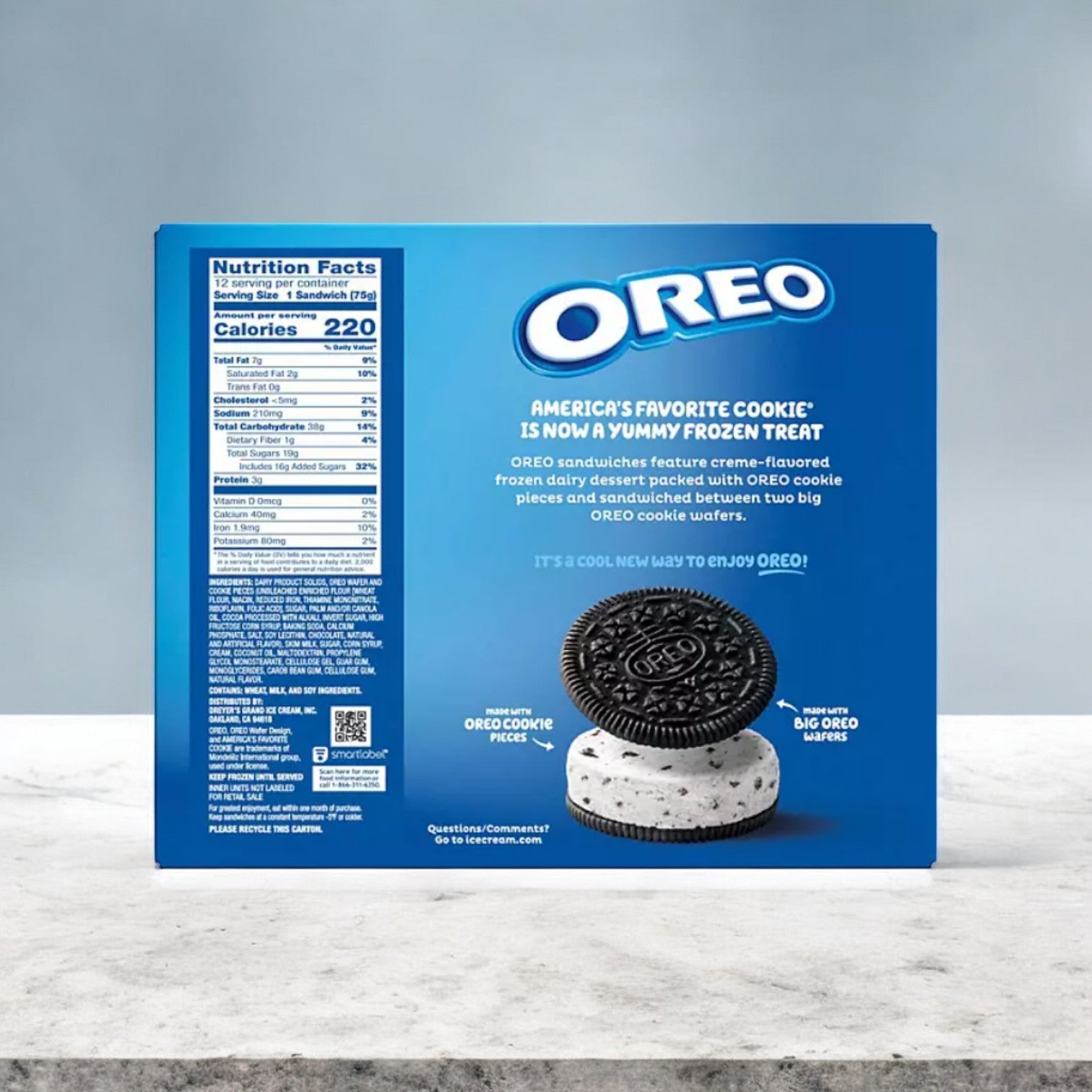 A box of Nabisco Oreo Dairy Dessert Sandwiches rests on a gray surface, featuring nutritional facts on the left panel and an enticing image on the front. This frozen treat offers a creamy dairy dessert filling, ideal for satisfying sweet cravings.