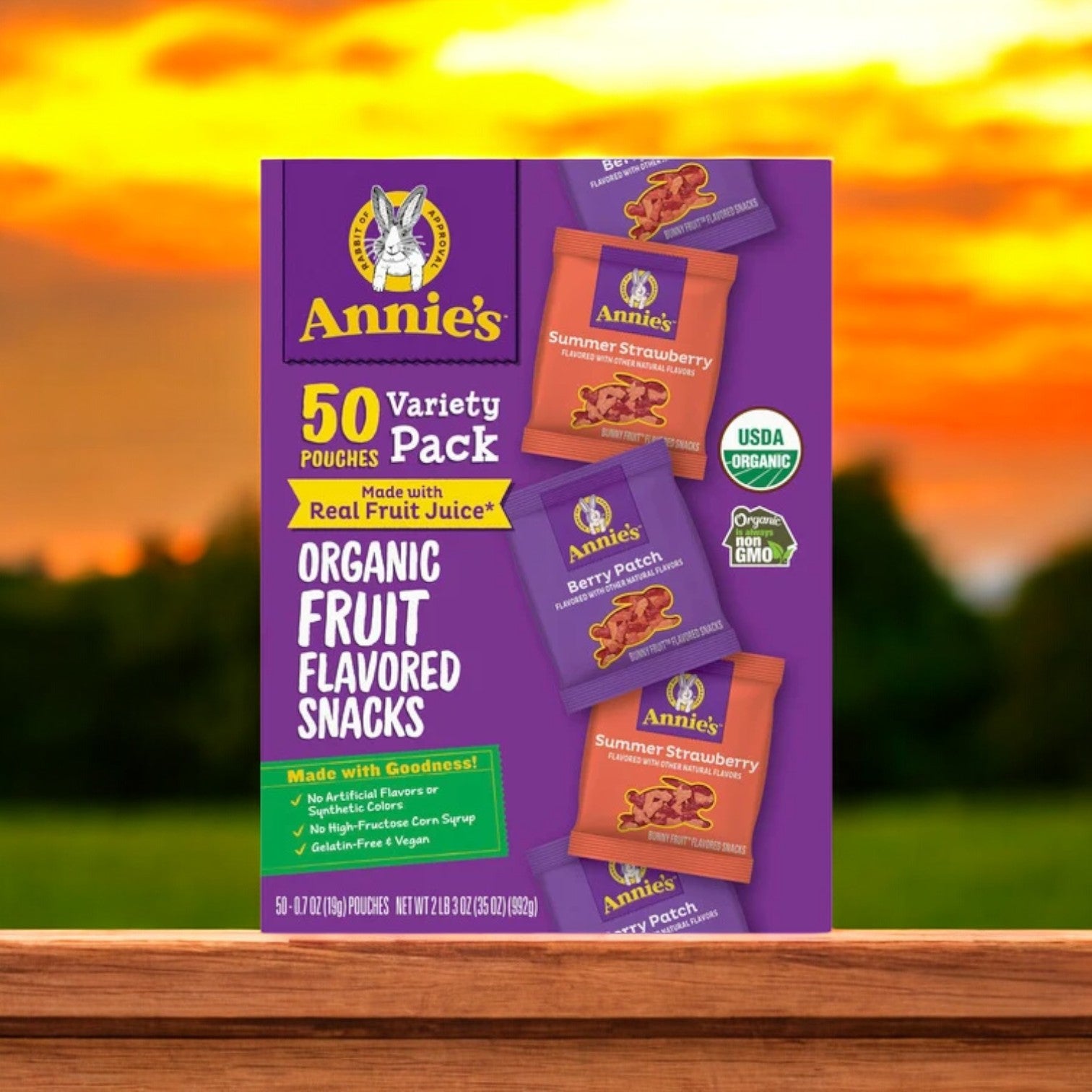 Box of Organic Annie's Fruit Snacks Variety (50-Count), featuring assorted flavors such as summer strawberry and berry patch, made with real fruit juice and elegantly displayed on a wooden surface.