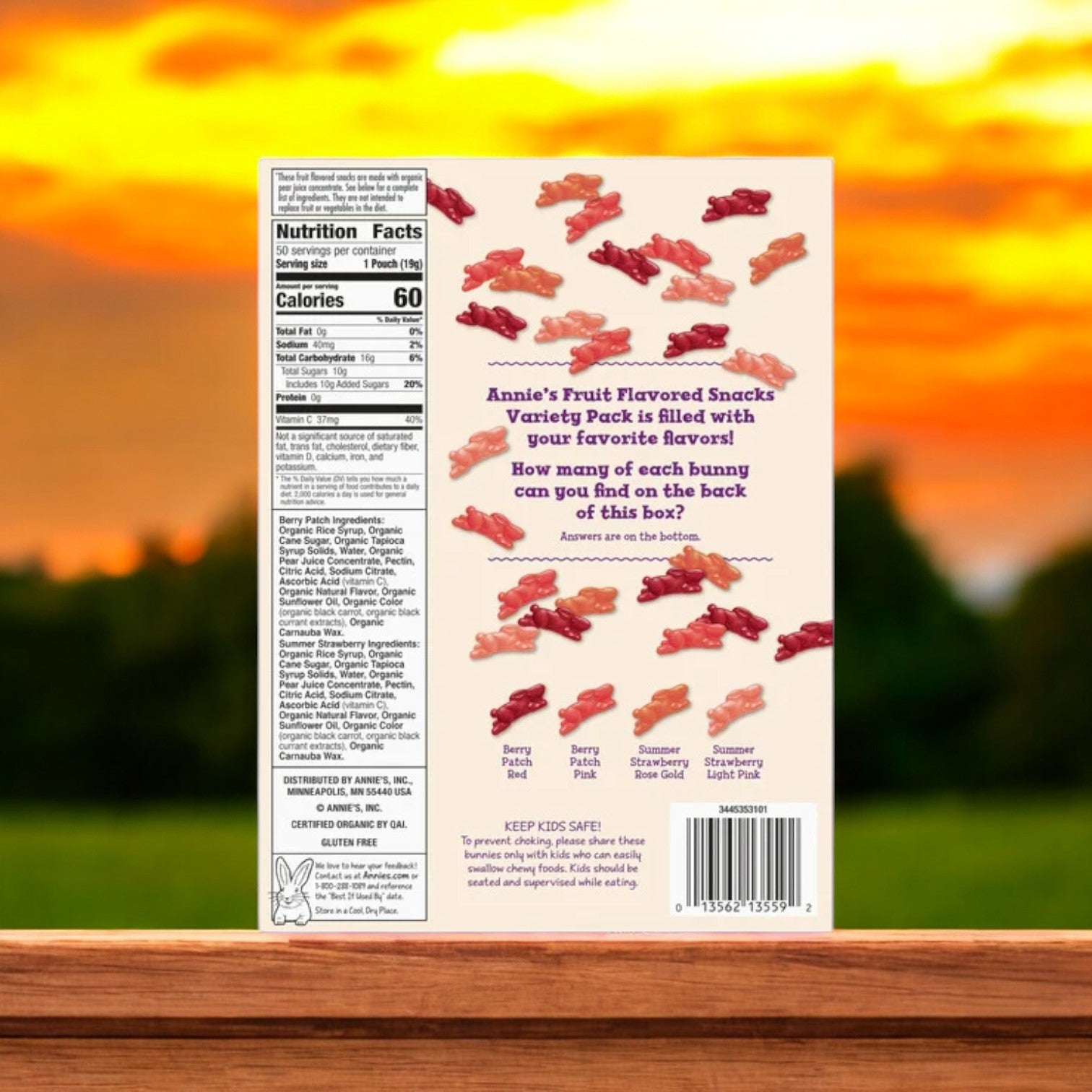 The Organic Annie's Fruit Snacks Variety (50-Count) - 1 Box is designed with vibrant illustrations of bunnies and includes nutritional facts and descriptions of assorted flavors, all set against a breathtaking sunset outdoors.