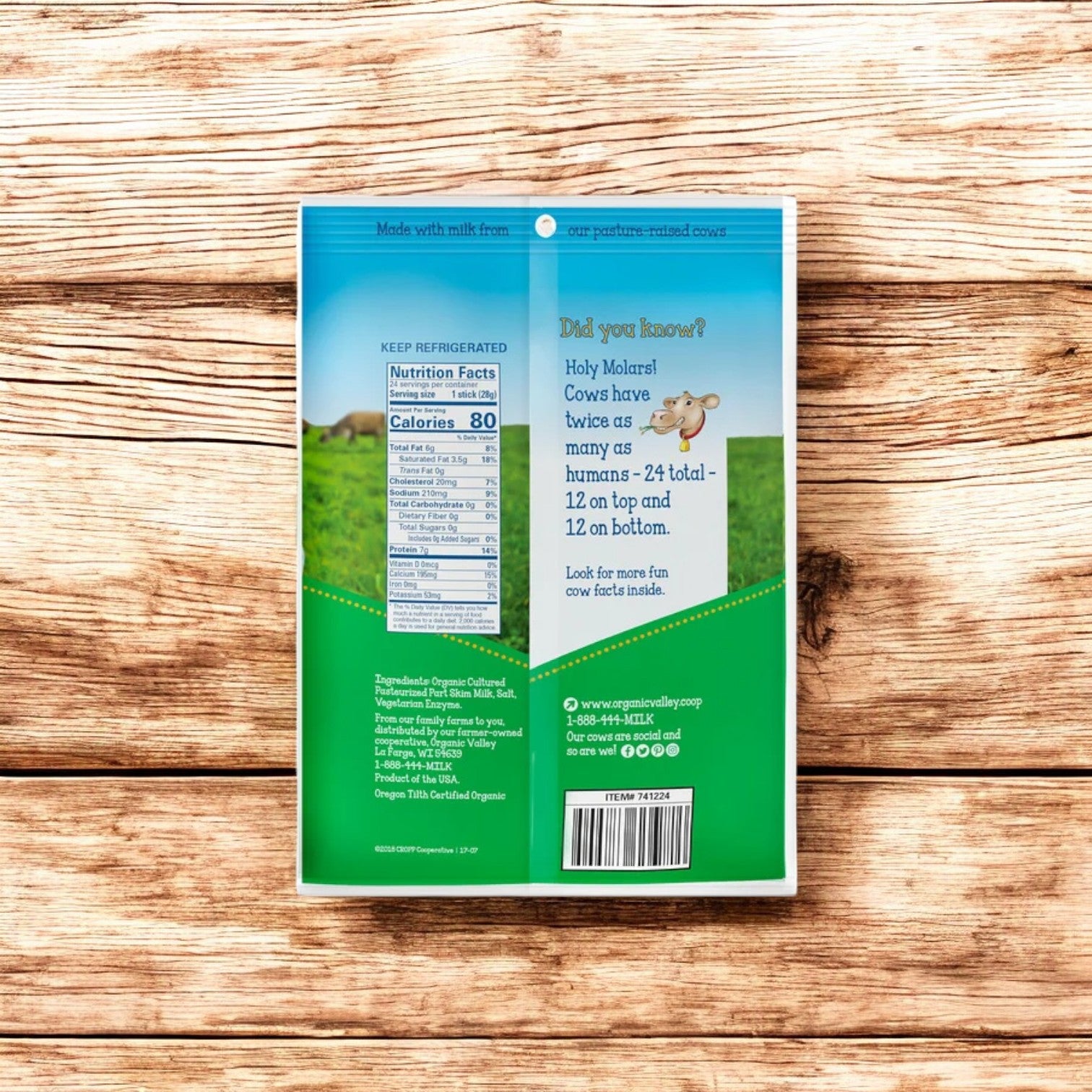 The back of an Organic Valley Stringles Organic String Cheese package showcases nutritional facts, storage instructions, a fun fact about cows, and contact information. The case includes 5 bags with a total of 120 delicious mozzarella cheese sticks. This appealing package is displayed on a wooden surface.