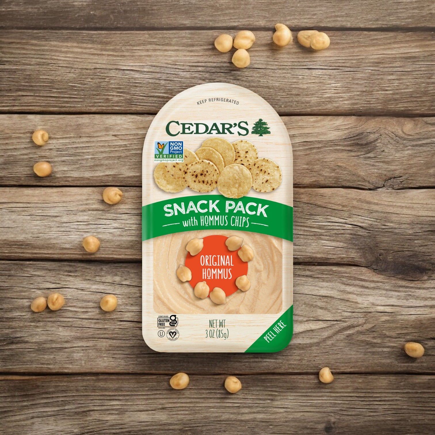 Cedar's Snack Pack with Hummus Chips - 1 Count placed on a wooden surface, surrounded by scattered chickpeas.