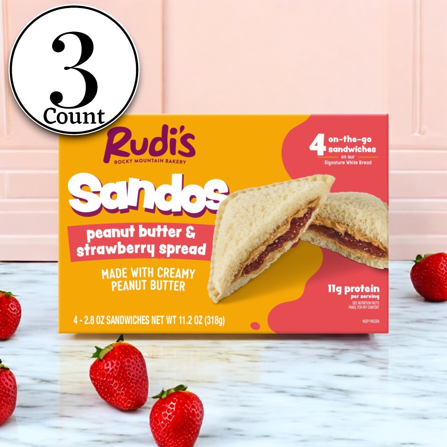 Enjoy a box of Rudi's Peanut Butter and Strawberry Spread Sandos by Rudi's Rocky Mountain Bakery. This 11.2 oz pack contains 3 packs of 4 delightful vegan snacks, neatly displayed with fresh strawberries on a white surface.