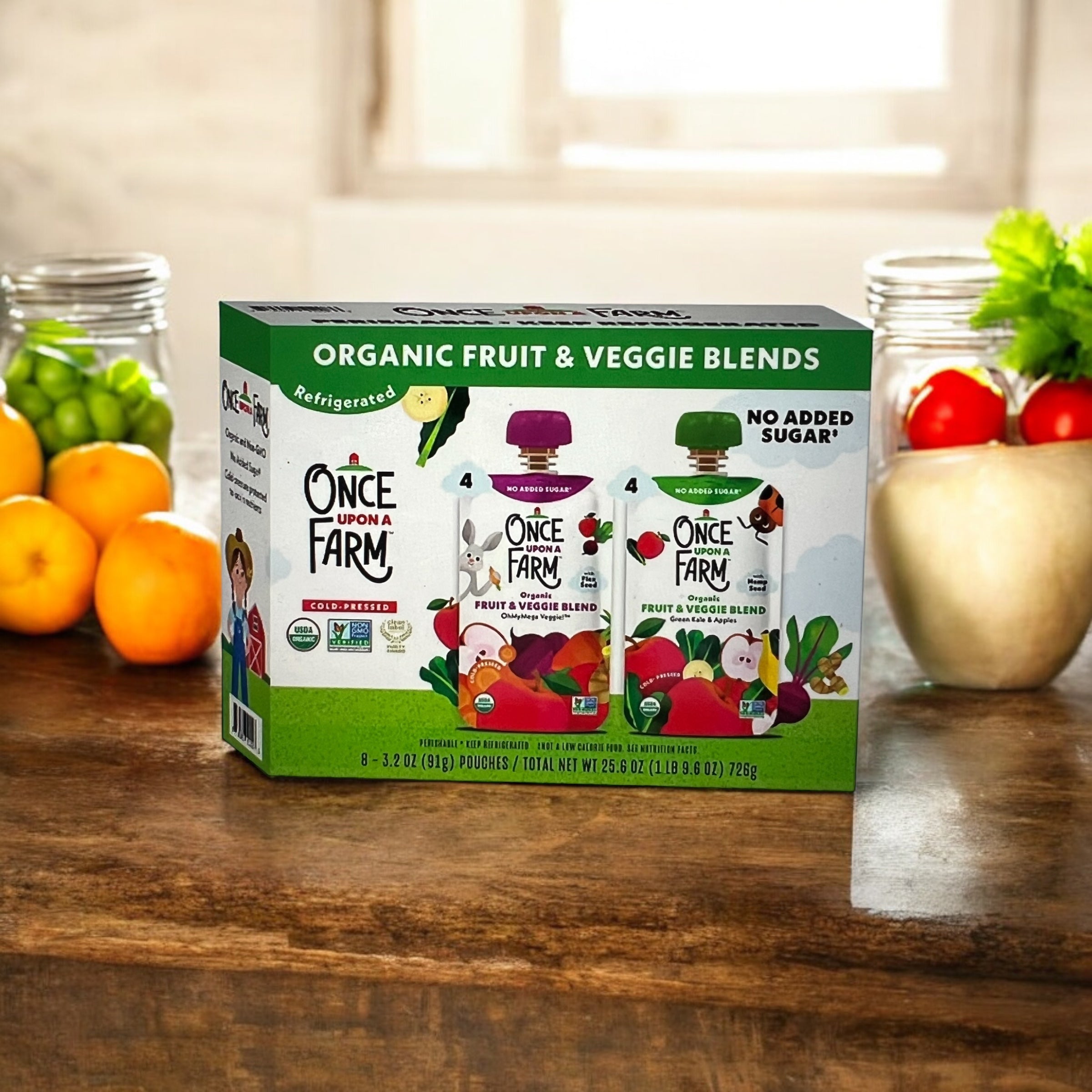 A box of Once Upon a Farm Organic Fruit & Veggie Blend Variety Pack, featuring 4 OhMyMega Veggie and 4 Green Kale and Apples pouches, sits on a wooden table with fresh produce in the background. This nutritious snack from Once Upon a Farm offers a vibrant selection to keep snack time both healthy and delicious.