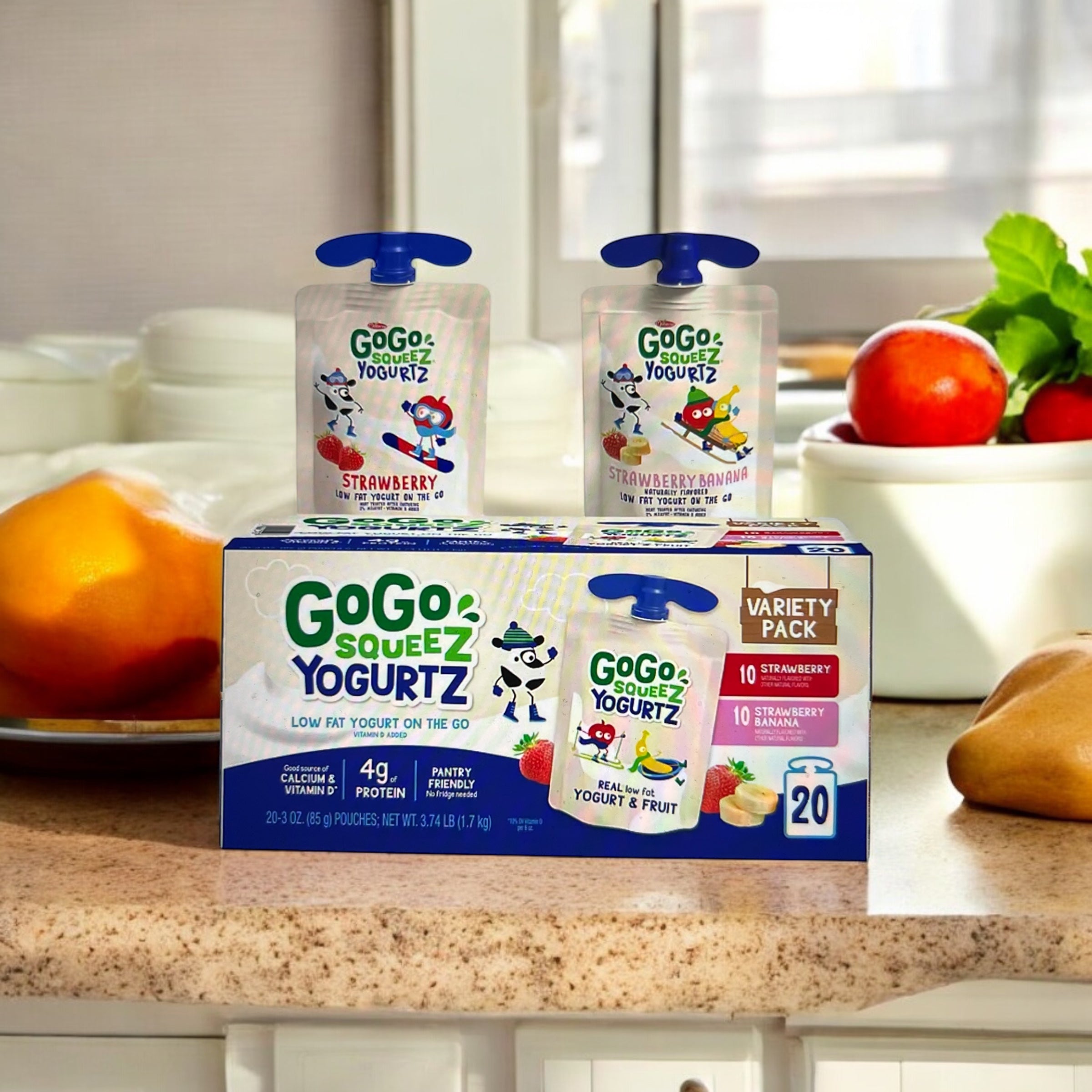 A box of Easy Lunches GoGo Squeez Yogurtz, in a variety pack with Strawberry and Strawberry Banana flavors, is on a kitchen counter. Two yogurt pouches are standing on top of the box.