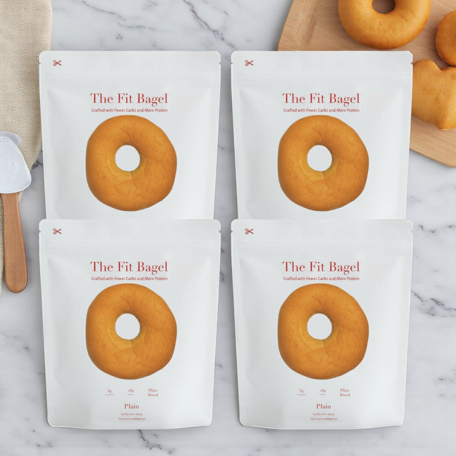 Four bags of The Fit Bagel – Plain Bagels (16 bagels total) are displayed on a marble surface, ready to help you craft delicious, healthy breakfast sandwiches. Brand: The Fit Bagel.
