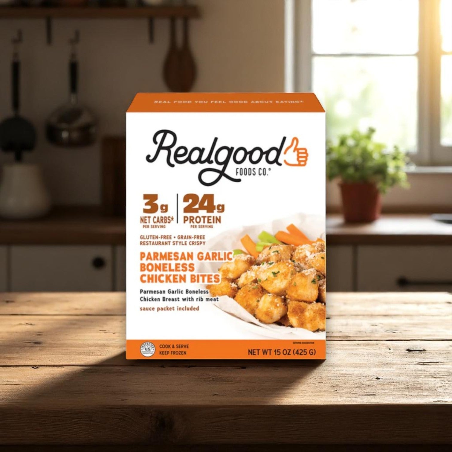 A 3-pack bundle of Real Good Foods Low Carb, High Protein gluten-free chicken favorites sits on a wooden table in a sunlit kitchen.