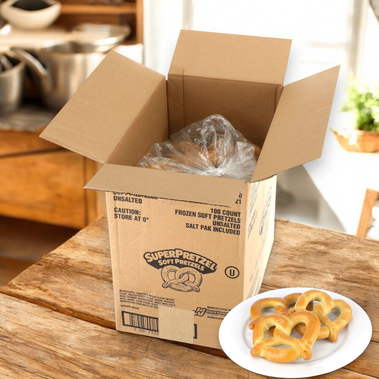 A cardboard box labeled "Super Pretzel" is open, displaying a tempting assortment of golden "SUPERPRETZEL Soft Baked Pretzels" (100 Count, 2.5 oz each). On the wooden kitchen table, a plate offers these irresistible treats, ideal for sharing with friends or family in bulk.