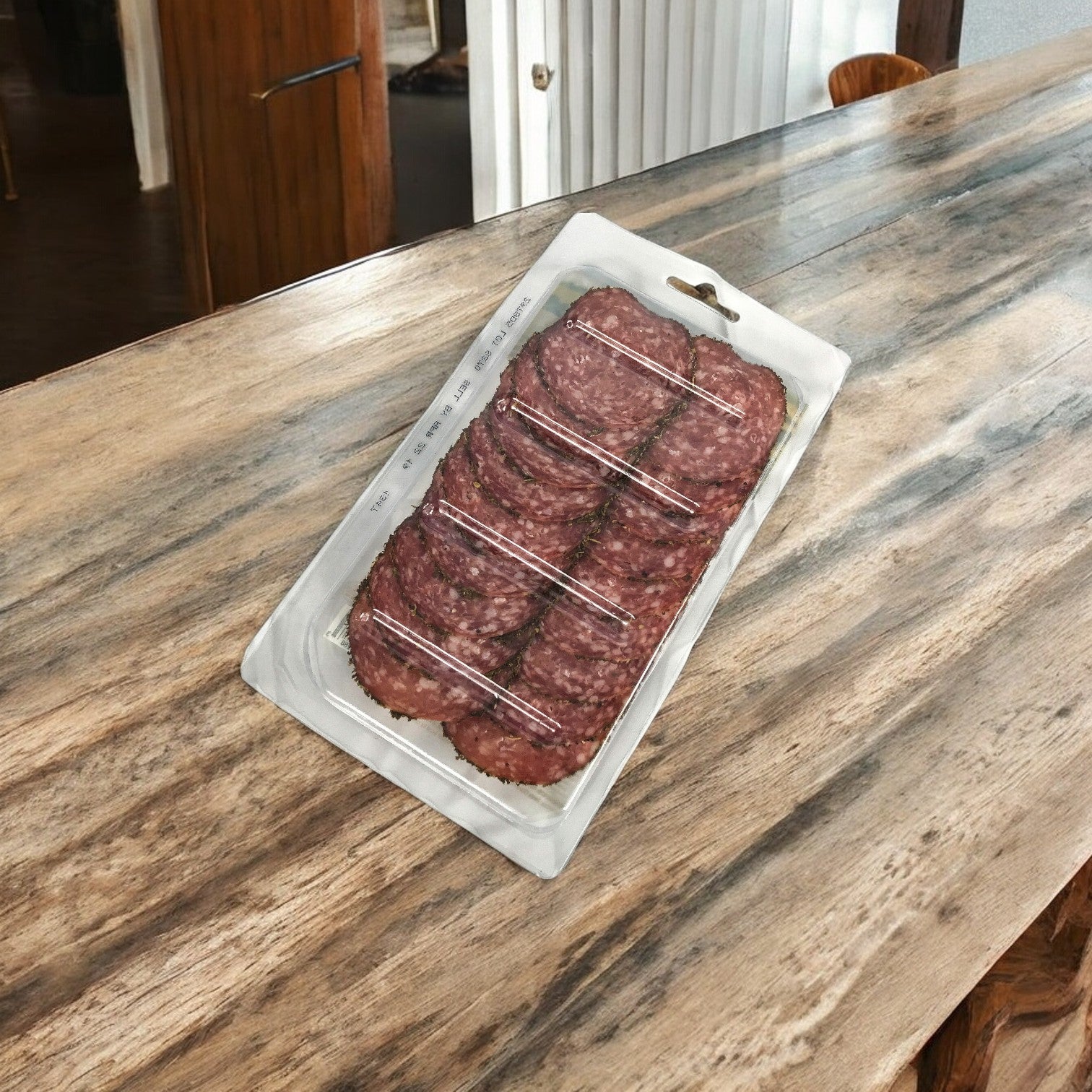 A vacuum-sealed pack of Busseto Salami Dry Herb De Provence, 3 oz. - 1 Count, highlighting its herb-infused flavor, is elegantly displayed on a wooden countertop, making it ideal for charcuterie boards.