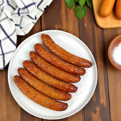 Six Amylu ABF Chicken Meatballs with Parmesan & Basil are neatly arranged on a white plate with a checkered cloth, green leaves, and salt nearby. More Amylu meatballs are placed beside them. Product: 46 oz-3 Count by Amylu.