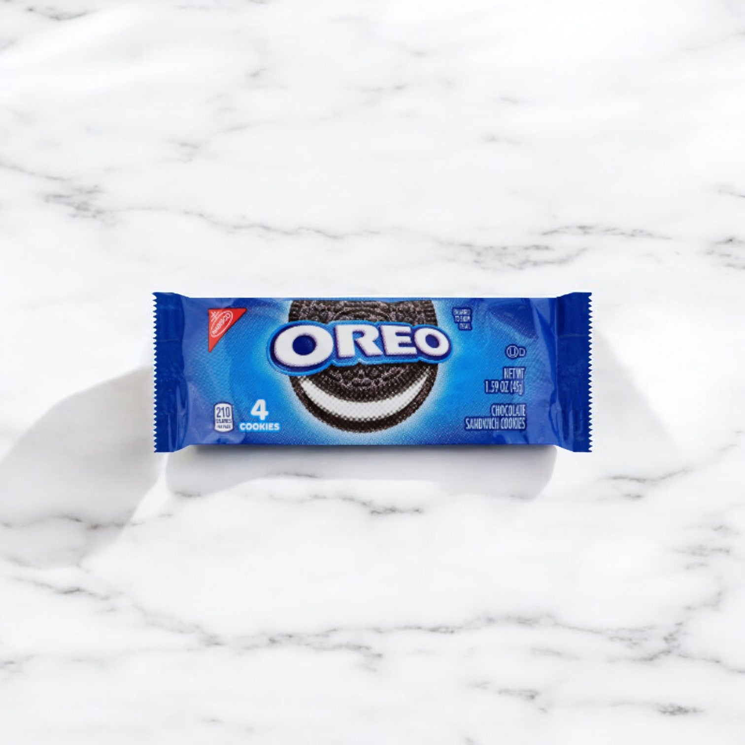 A small blue bag of Nabisco's OREO Chocolate Sandwich Cookies, containing four chocolate wafers with a white creme filling, is placed on a white marble surface.