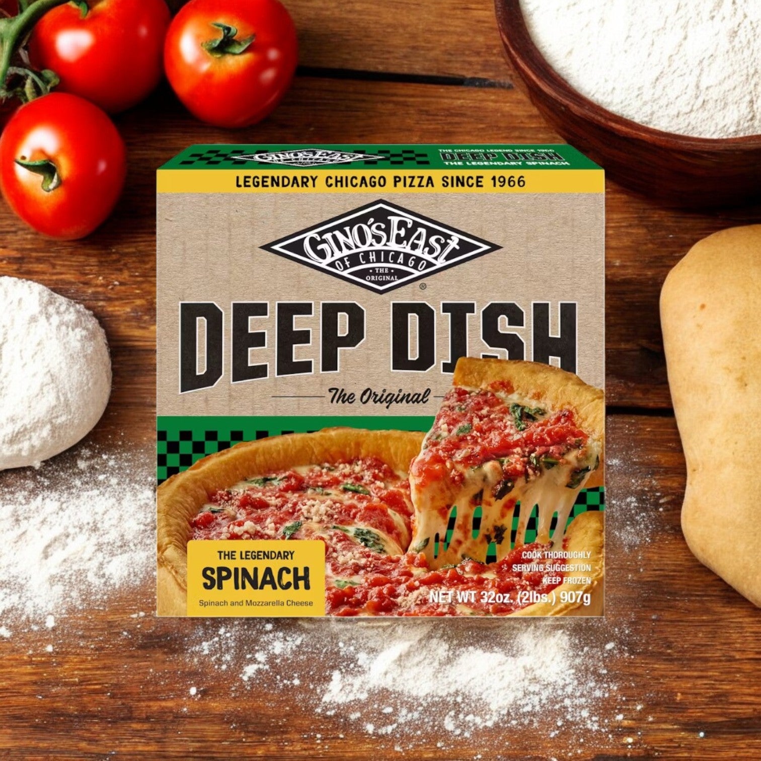 A box of Gino's East 3-Pack Combo, featuring Spinach Deep Dish, rests on a wooden surface surrounded by fresh tomatoes, flour, and dough.