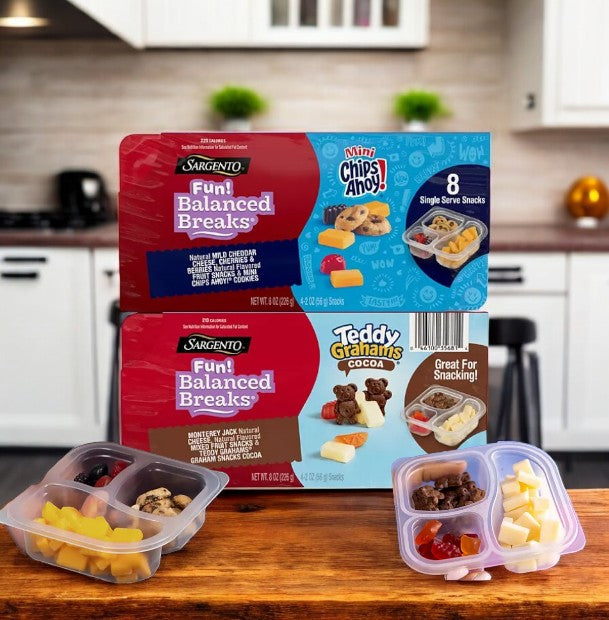 Three packages of Sargento Fun Balanced Breaks Variety Pack, totaling 24 packs, complement Tupperware filled with similar snacks in the kitchen. This variety pack by Sargento is perfect for any snacking occasion with its delightful blend.