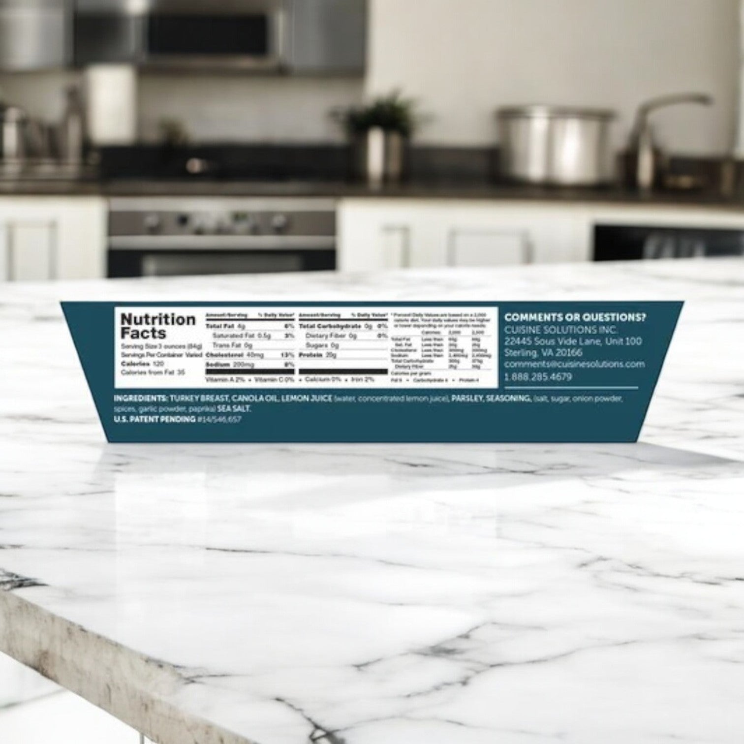 A side view of a Cuisine Solutions Sliced Turkey Breast with Citrus Herbs-1 Count package on a marble counter shows nutrition facts and ingredients. Blurred kitchen appliances in the background enhance the culinary ambiance.