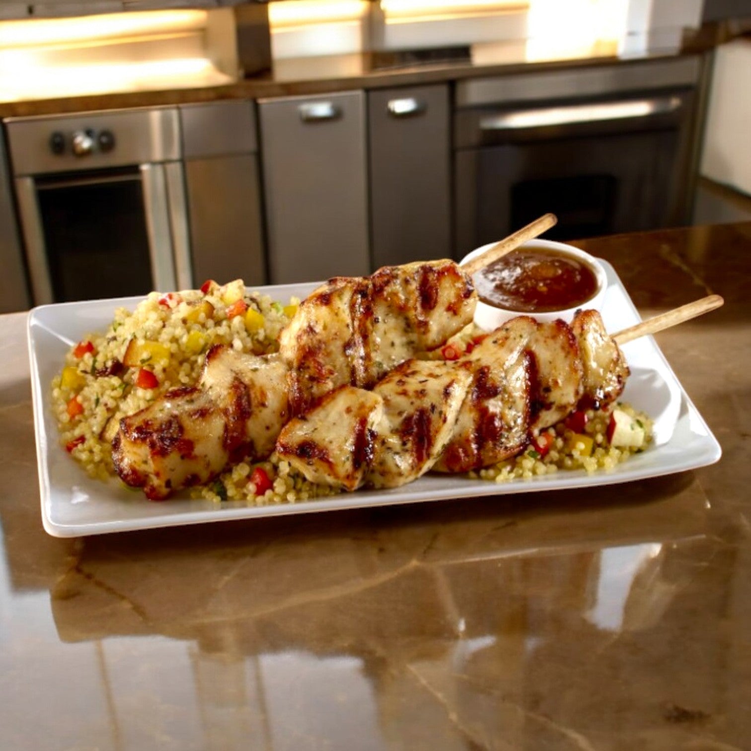 Sysco Chicken Breast Skewer Grilled Halal served with rice and vegetables, and a small sauce cup, rests on a marble kitchen countertop.