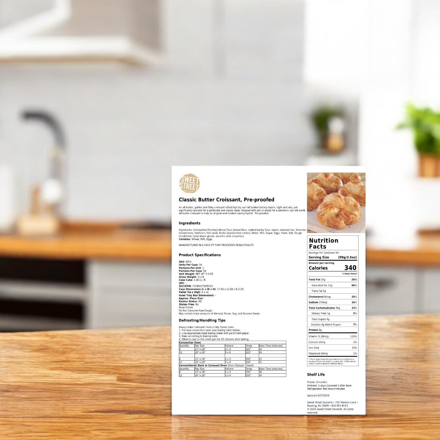 A printed sheet featuring Sweet Street Croissant All Butter Preproofed 54-pack, 3.5OZ by Sweet Street is displayed upright on a kitchen counter with a blurred background.