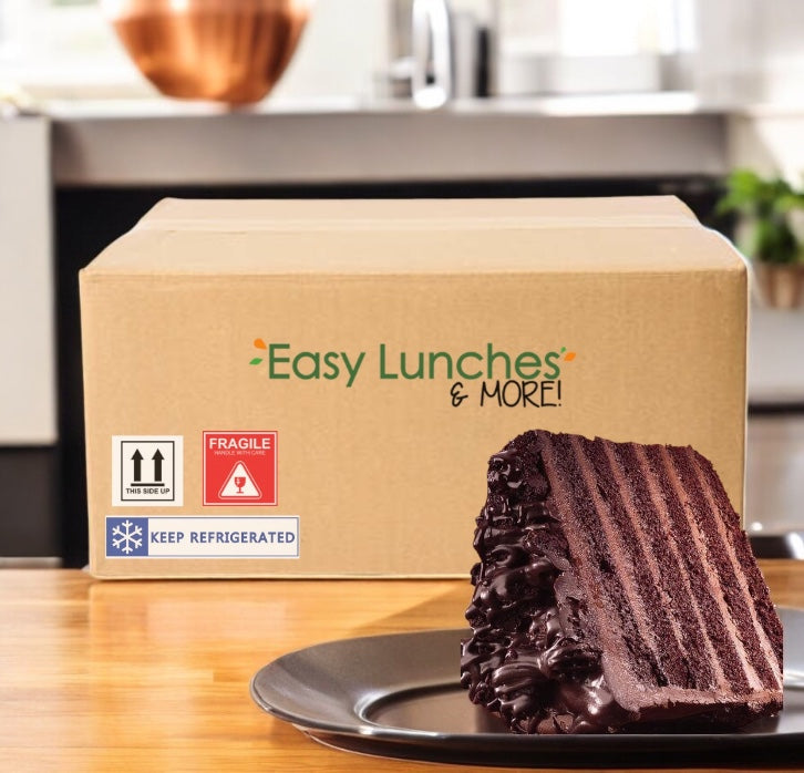 A box labeled "Easy Lunches & More!" sits on a kitchen counter next to a slice of Sweet Street Uncut Chocolate Layer Cake – 2 Extra-Large Cakes (128 oz each), highlighting Sweet Street’s premium, customizable dessert option.
