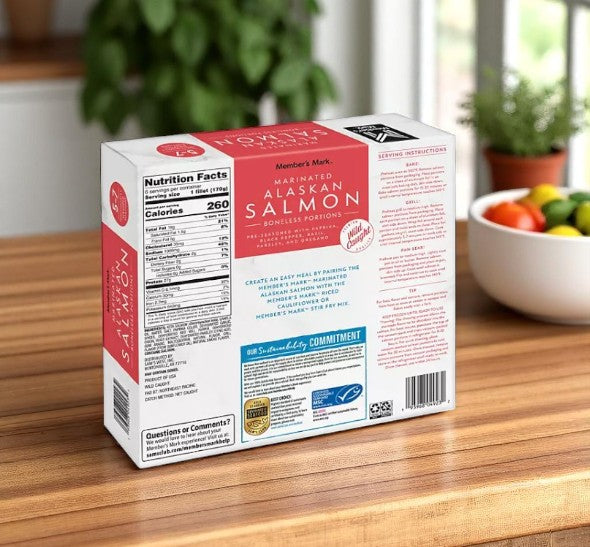 A box of Member's Mark Wild Caught Boneless Marinated Alaskan Salmon, Frozen (2.25 lbs., 3 Cases), is on a wooden kitchen counter beside a bowl of assorted vegetables.