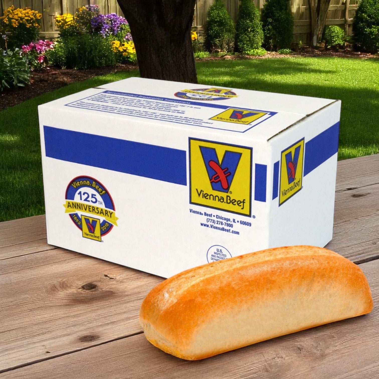 A Vienna Beef-branded box sits on a wooden table outdoors, with a Turano Vienna Beef Famous Chicago Style French Bread – 6" roll in front. A green lawn and garden are visible in the background, evoking a classic foodservice setting.